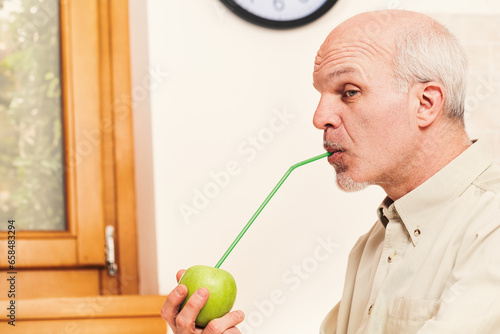 Jestful elder in kitchen, focused on apple photo