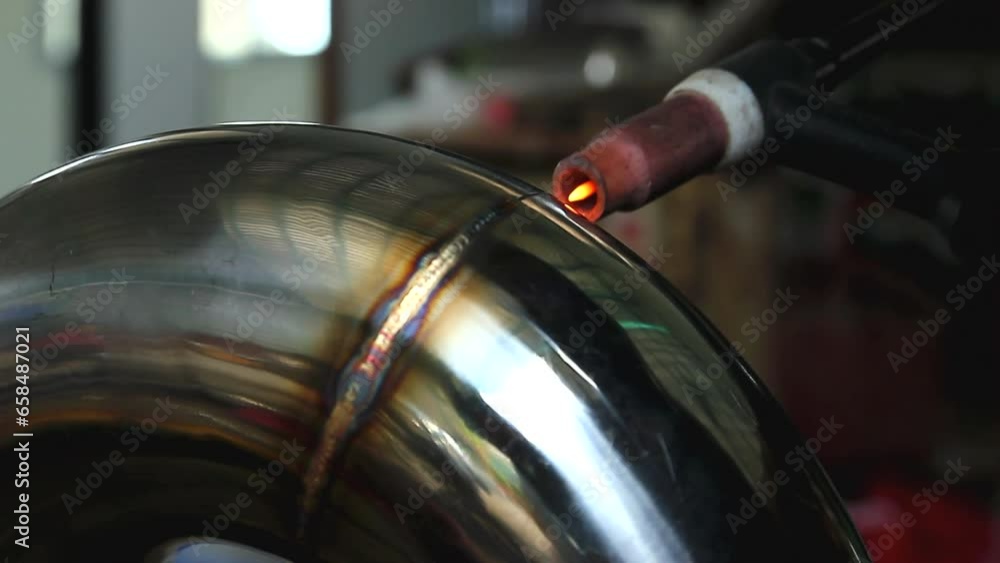 Welder is welding the stainless steel pipes in the factory Welder is welding the stainless steel pipes in the factory