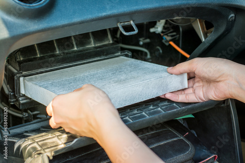 Technician hands holding air filter in car repair service.