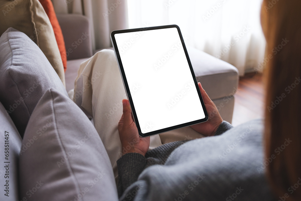 Mockup image of a woman holding digital tablet with blank desktop screen while lying on a sofa at home Mockup image of a woman holding digital tablet with blank desktop screen while lying on a sofa at home