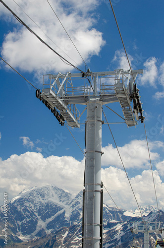 The support of a high-altitude cable car on the background of snow-capped mountains. A funicular in the mountains takes people to the top.