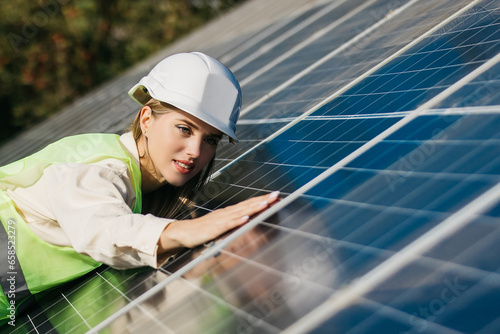 Close-up of a young female engineer checking the operation of the sun and the cleanliness of photovoltaic solar panels. Concept renewable energy, technology, electricity, services, green