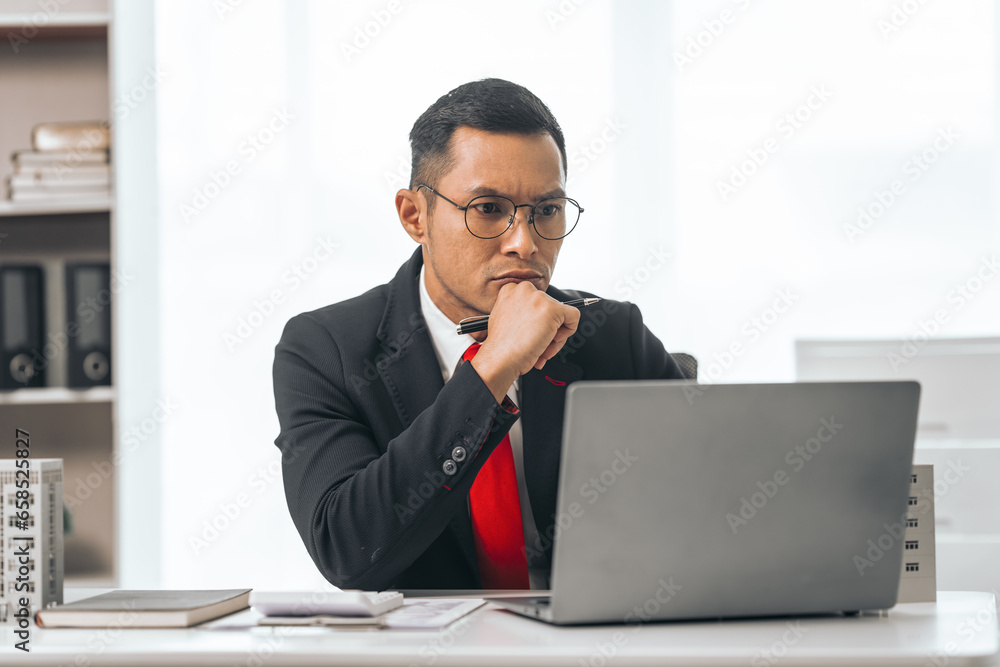 Agent presents contracts for property purchase or lease. Businessman asian indian people showcases miniature model home, signifying secure property insurance. Desk scene in a home sales office. Agent presents contracts for property purchase or lease. Businessman asian indian people showcases miniature model home, signifying secure property insurance. Desk scene in a home sales office.