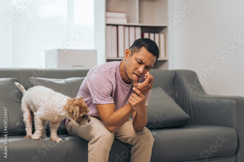 Middle-aged Asian Indian man with Wrist pain while sitting on sofa