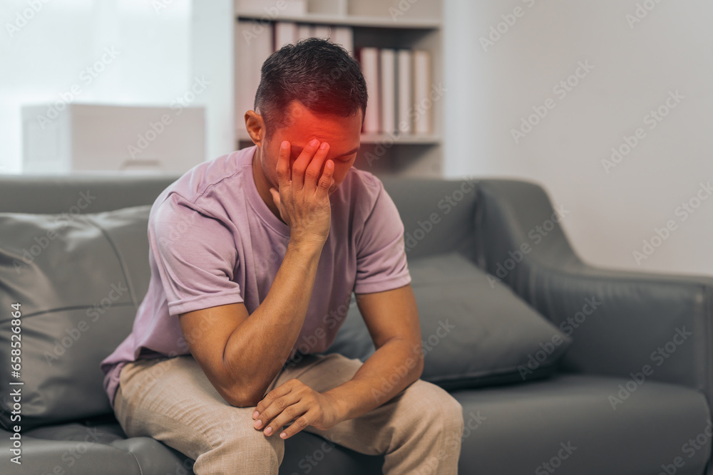 Middle-aged Asian Indian man with psychosis, depression, headache, migraine, sitting on sofa. Middle-aged Asian Indian man with psychosis, depression, headache, migraine, sitting on sofa.
