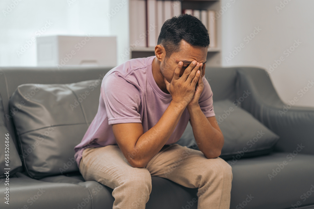 Middle-aged Asian Indian man with psychosis, depression, headache, migraine, sitting on sofa. Middle-aged Asian Indian man with psychosis, depression, headache, migraine, sitting on sofa.