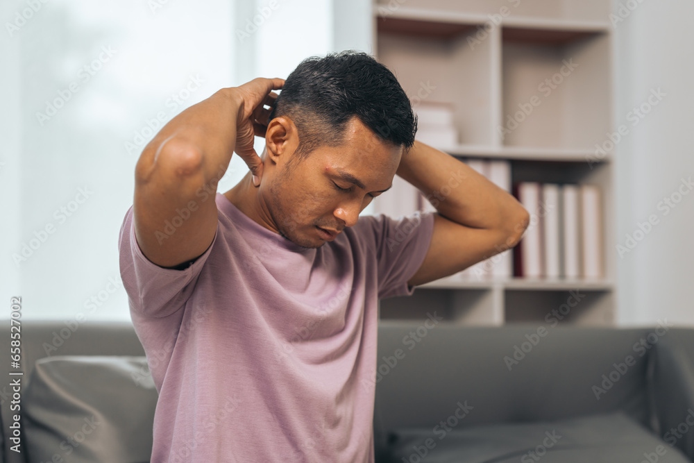 Middle-aged Asian Indian man suffering from back pain, spine and neck pain. sitting on the sofa Middle-aged Asian Indian man suffering from back pain, spine and neck pain. sitting on the sofa