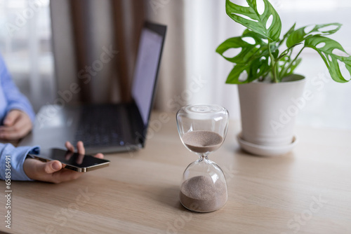 Hourglass on the table for business deadline. Time concept photo