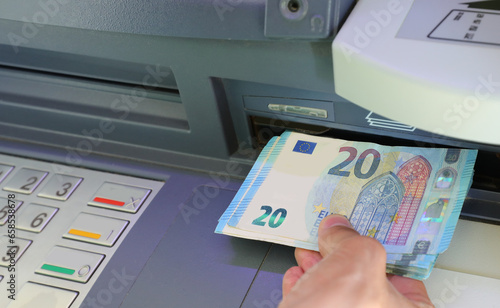 фотографія Hand of person withdrawing twenty euros banknotes in a bank ATM i