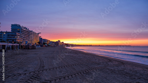 Amazing view of a fiery sunrise with multicolored clouds. Sea waves along the seashore at sunrise. Morning time. Ocean view. La Baule-Escoublac, France