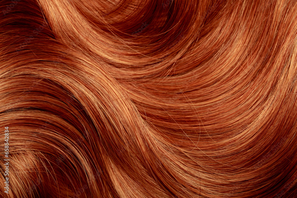Fototapeta premium Red hair close-up as a background. Women's long orange hair. Beautifully styled wavy shiny curls. Hair coloring bright shades. Hairdressing procedures, extension.