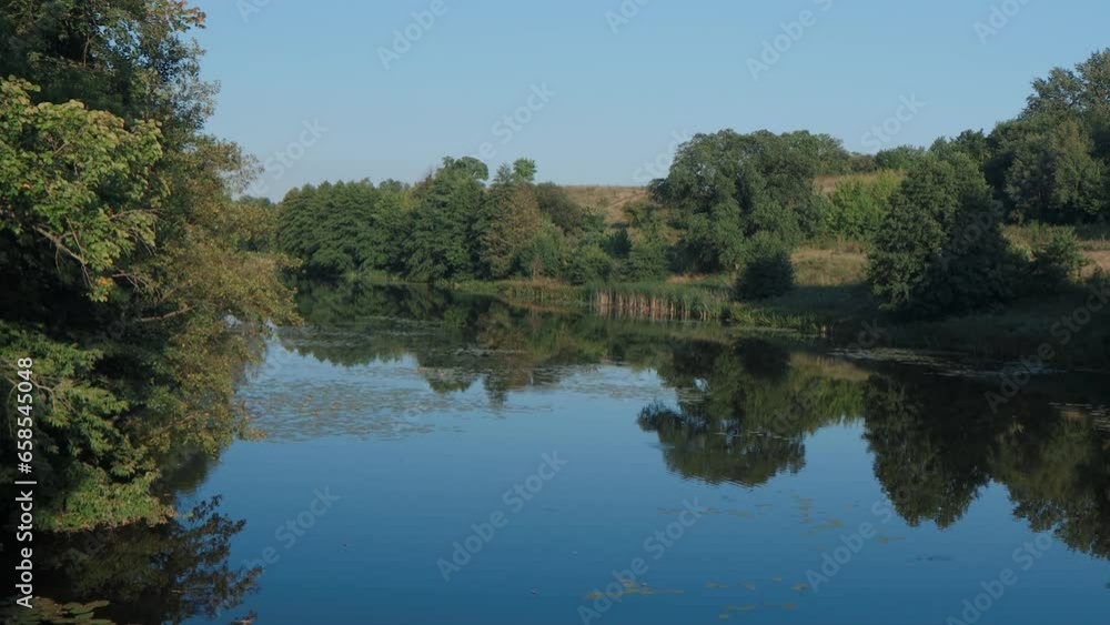 Beautiful landscape with river and forest. The trees are covered with green leaves. Beautiful blue sky. Water lilies on the water. Rapid flow of the river. Beautiful river bank. Beautiful landscape with river and forest. The trees are covered with green leaves. Beautiful blue sky. Water lilies on the water. Rapid flow of the river. Beautiful river bank.