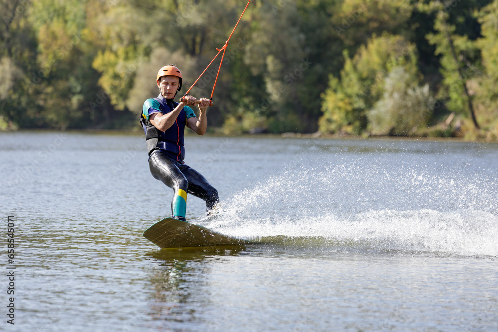 Young wakeboarder surfing along the river