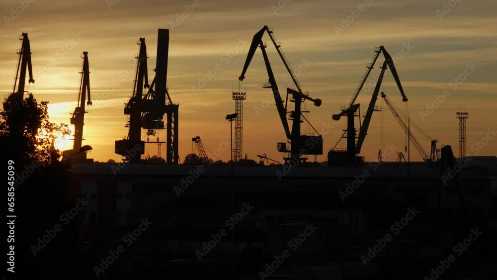 A panorama of cranes silhouetted against a sunset sky in Ventspils shipyard A panorama of cranes silhouetted against a sunset sky in Ventspils shipyard