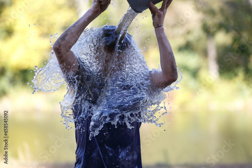 A man pouring bucket of water on his head as an element in obstacle race