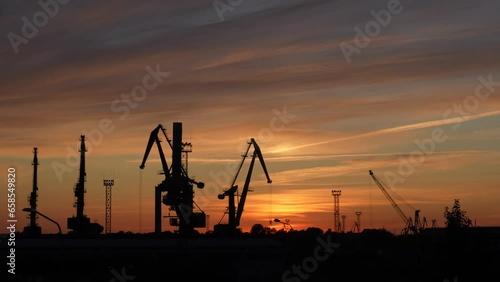 A stunning sunset view of cranes standing in transport terminal.