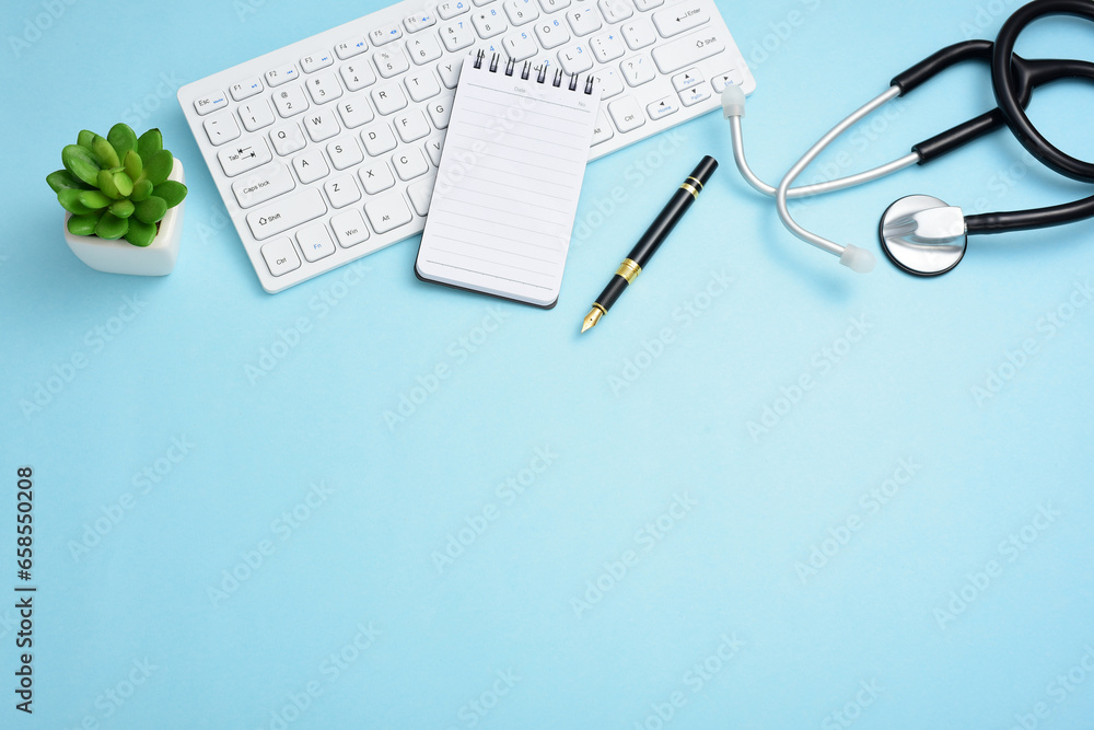 Stethoscope, computer keyboard, pen, note pad, and greenery on a blue background. Stethoscope, computer keyboard, pen, note pad, and greenery on a blue background.