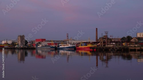 A group of fishing boats docked in a harbor after sunset on a summer day