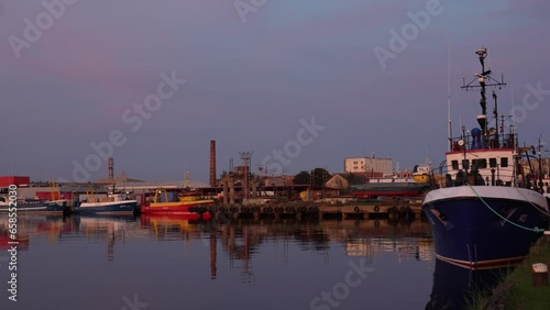 Boats docked in a picturesque harbor after a peaceful sunset