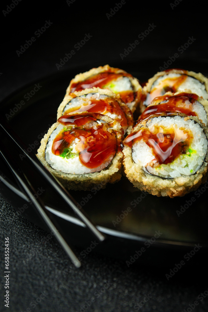 Sushi rolls in a dark plate on a black background Sushi rolls in a dark plate on a black background