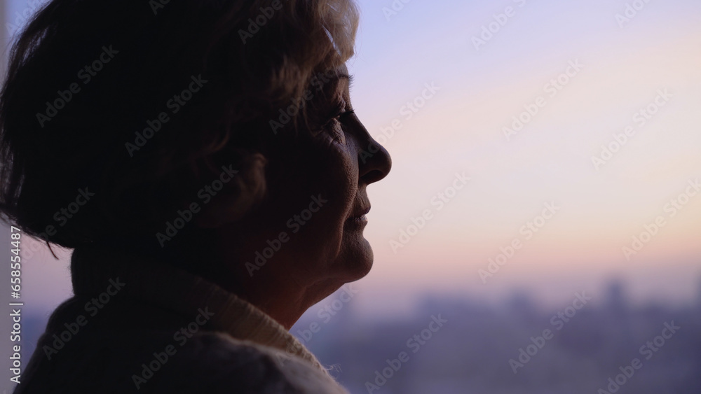 An unhappy wrinkled woman looking out the window, suffering from loneliness in her senior age An unhappy wrinkled woman looking out the window, suffering from loneliness in her senior age