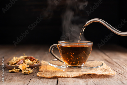 Make a cup of hot tea or a glass of chrysanthemum tea. and chrysanthemums lay on the wooden table Pouring healthy drinks, herbal drinks and medical concept