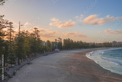 Sydney northern beaches main Manly beach facing pacific ocean on a sunny summer day with crowd of tourists and beachgoers relaxing and sufring.