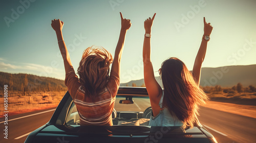 Des jeunes filles heureuses, assises de dos à l'arrière d'une voiture cabriolet en route, prêtes à voyager.  photo