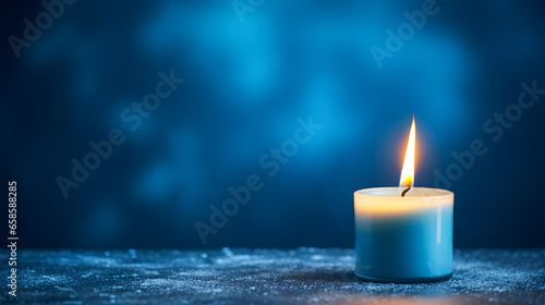 Une bougie allumée sur un table dans le cadre des fêtes de noël. En arrière plan, un fond bleu.  photo