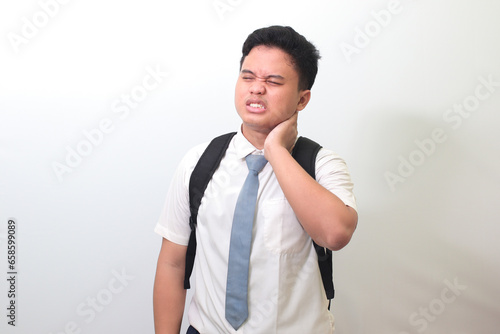 Indonesian senior high school student wearing white shirt uniform with gray tie touching his neck and expressing negativity. Isolated image on white background