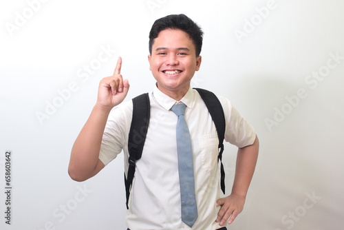 Indonesian senior high school student wearing white shirt uniform with gray tie pointing up with finger and reminding something to do. Isolated image on white background photo