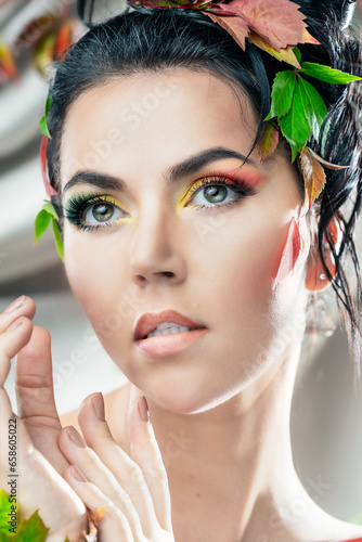 Glamorous portrait of a beautiful woman, Bright make-up. Autumn woman, decorated with autumn leaves