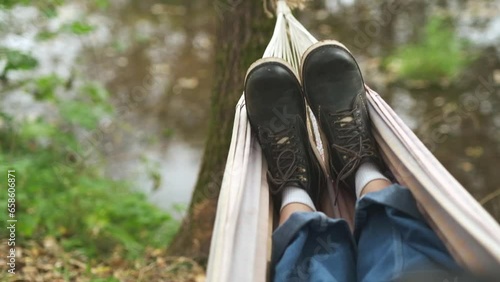 A man is resting in a hammock in a country house. A young guy lies in a hammock, dozing outdoors in the summer in the green of trees in the country