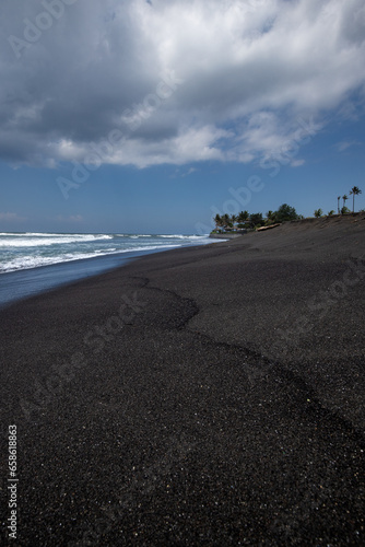 Black sand beach in Bali, natural with temples, boats (jukung) and waves at sunrise. Tropical environment in Indonesia in the morning © Jan