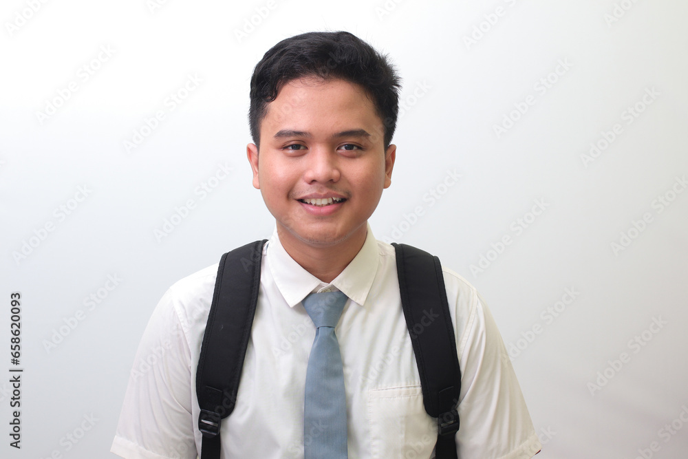 Indonesian senior high school student wearing white shirt uniform with gray tie smiling and looking at camera. Isolated image on white background Indonesian senior high school student wearing white shirt uniform with gray tie smiling and looking at camera. Isolated image on white background