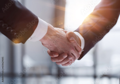Businessmen shaking hands standing in front of office windows