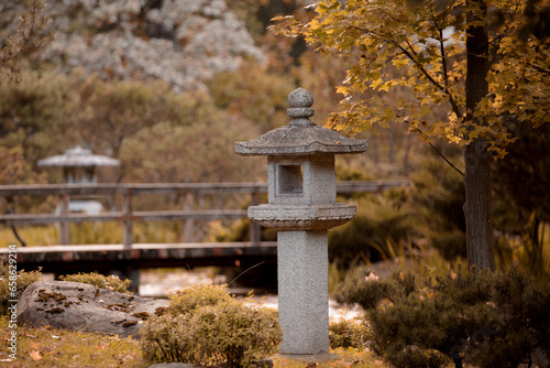 Traditional Japanese stone lantern in the autumn garden. Yellow autumn foliage