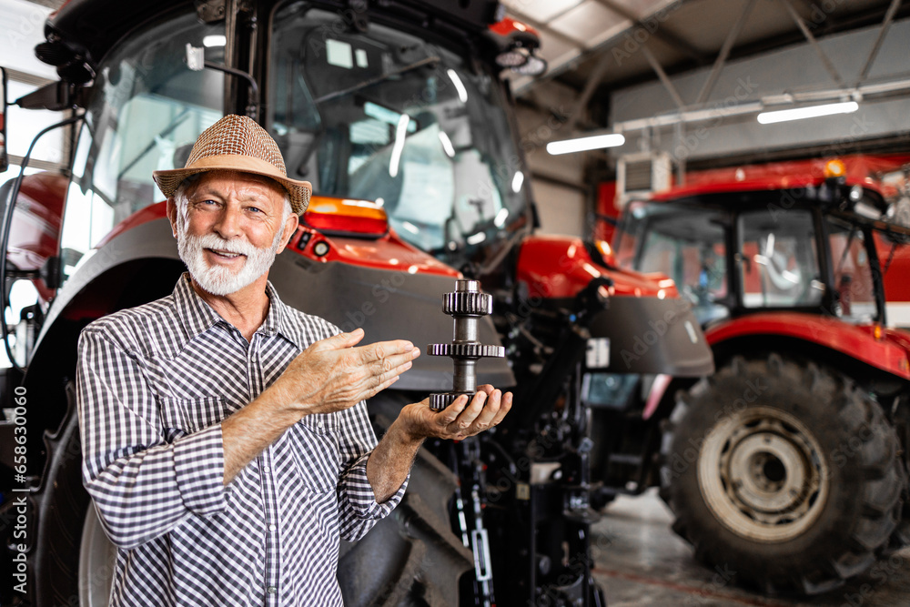 Farmer holding spare parts for tractor machine. Servicing and maintenance of agricultural machinery. - obrazy, fototapety, plakaty 