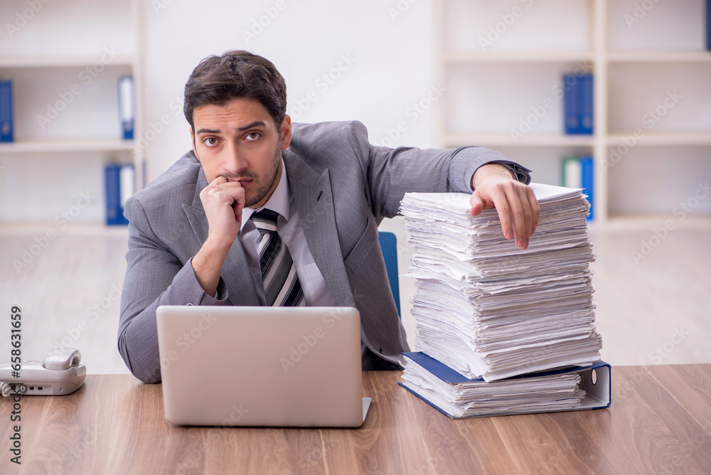Young male employee and too much work in the office Young male employee and too much work in the office
