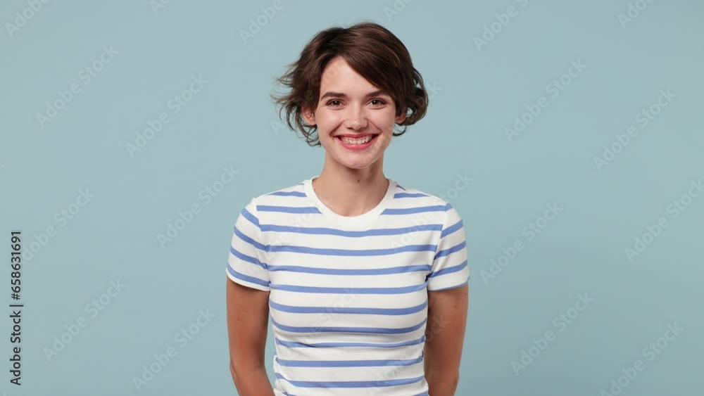 Young smiling happy cheerful positive cool fun woman wearing striped t-shirt casual clothes looking camera isolated on pastel plain light blue cyan color background studio portrait. Lifestyle concept Young smiling happy cheerful positive cool fun woman wearing striped t-shirt casual clothes looking camera isolated on pastel plain light blue cyan color background studio portrait. Lifestyle concept