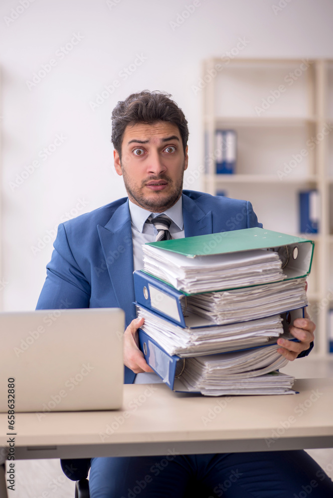 Young male employee and too much work in the office Young male employee and too much work in the office