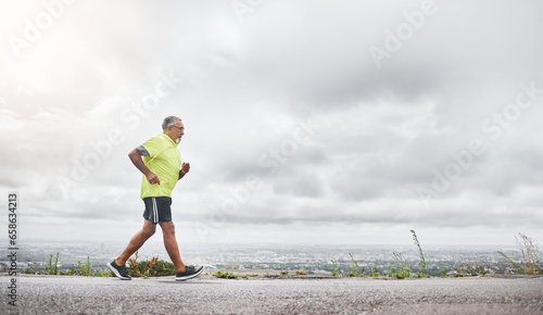 Senior man, running and fitness on road for outdoor exercise, training or workout on mockup. Mature male person, athlete or runner in sports, health and wellness on mountain for hiking or trekking