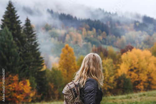 Hiking in autumn forest. Woman during hike in mountain. Fog weather