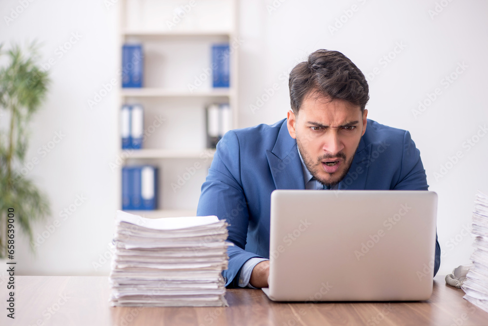 Young male employee and too much work in the office Young male employee and too much work in the office