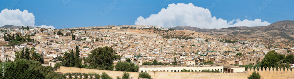 Beautiful panoramic view of the old Medina in Fes, Morocco (Fes El Bali Medina), a sea of buildings made of earthy tones. It's a bustling maze of life, with people and markets nestled in its heart