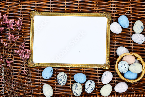 golden picture or photo frame mockup with pink baby's breath, gypsophila and eggs on esparto halfah background. happy easter concept photo