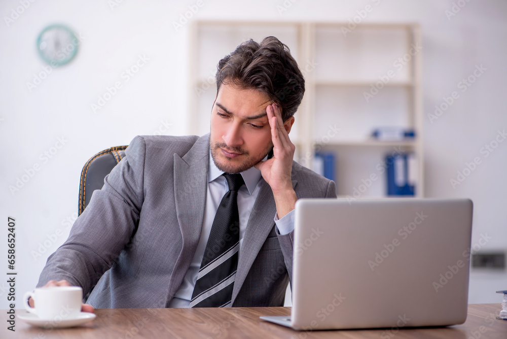 Young male employee drinking coffee during break Young male employee drinking coffee during break