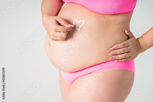 Wallpaper Mural Pregnant woman in pink underwear applying skin stretch mark cream on her belly on gray background, maternity underwear, pregnancy skin care concept Torontodigital.ca