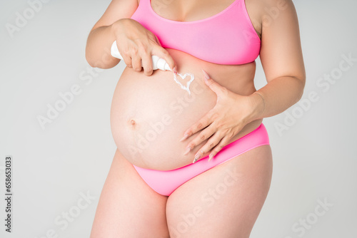 Wallpaper Mural Pregnant woman in pink underwear applying skin stretch mark cream on her belly on gray background, maternity underwear, pregnancy skin care concept Torontodigital.ca