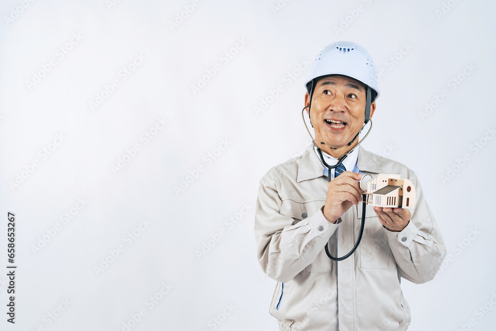 住宅を聴診器で検査する作業服の中年男性 作業員 建設業者 住宅を聴診器で検査する作業服の中年男性 作業員 建設業者